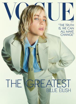 Billie Eilish wearing a tan suit and striped yellow tie leaning forward on the November 2024 cover of Vogue