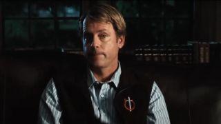 Greg Kinnear wincing in a vest in Salvation Boulevard