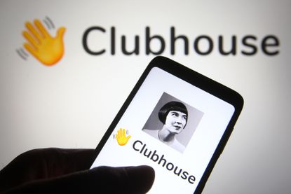 In this photo illustration the Clubhouse logo is seen on a smartphone and a pc screen