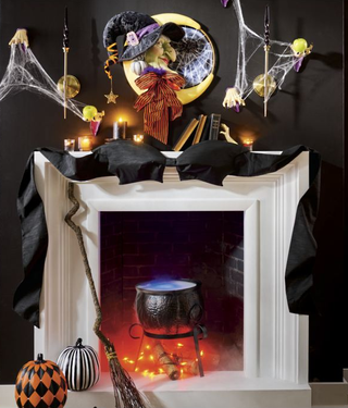 A fireplace mantel decorated with Halloween decor and a large bow