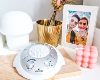 Homedics SoundSleep White Noise Sound Machine on bedside table with pink candle, mushroom light and photo frame