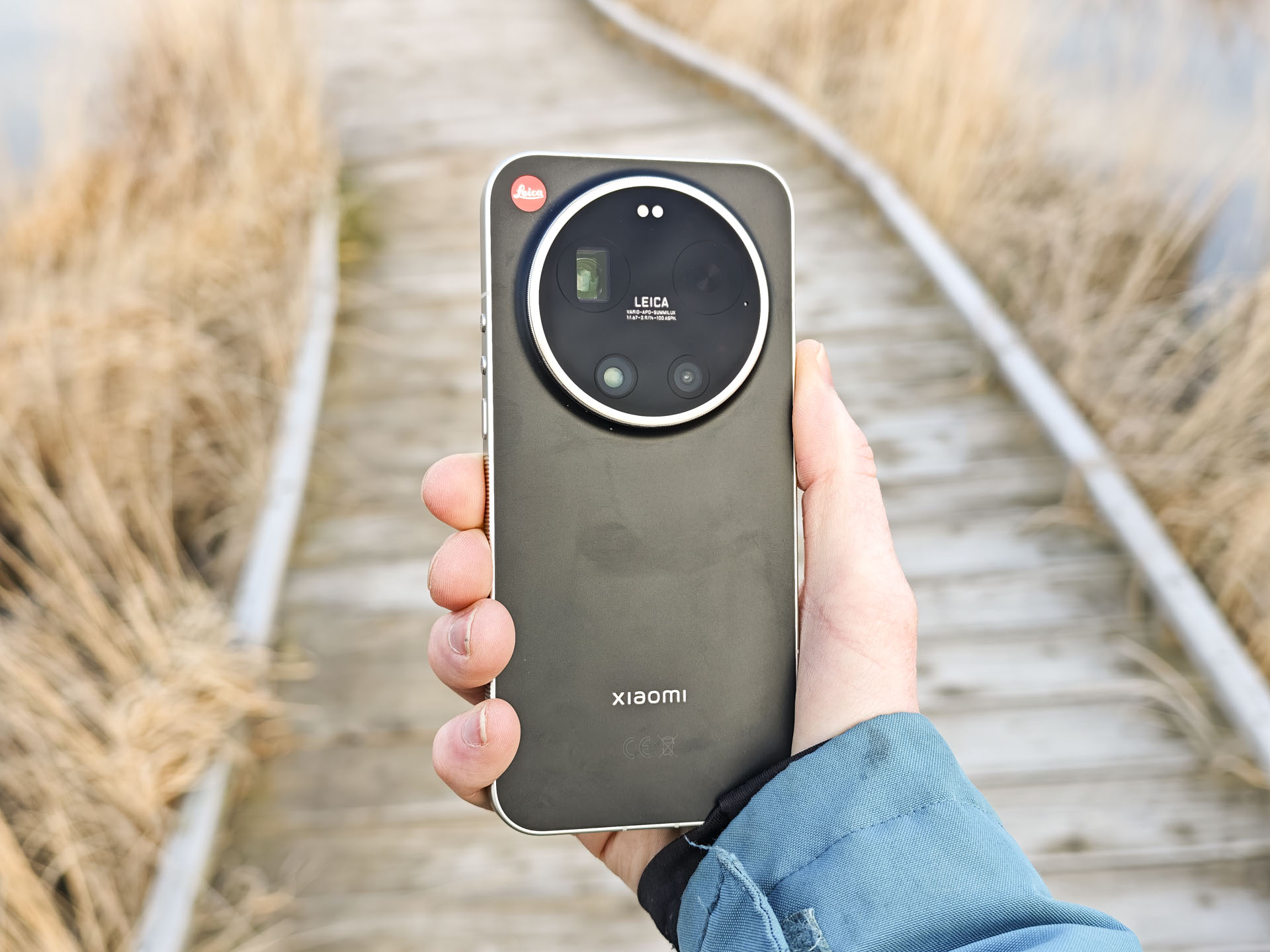 The Leica Leitzphone in person's hand with a wooden boardwalk backdrop