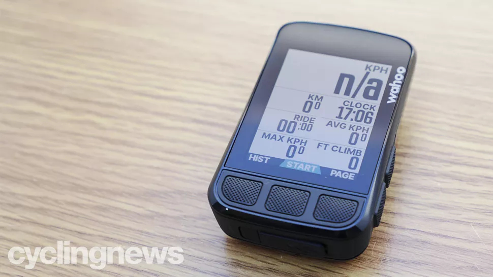 Wahoo Elemnt bolt placed on a wooden table top, with speed, distance, a clock, ride time, average speed, max speed and altitude climbed showing on the screen