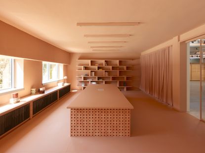 Large wooden table in centre of room and wall shelving