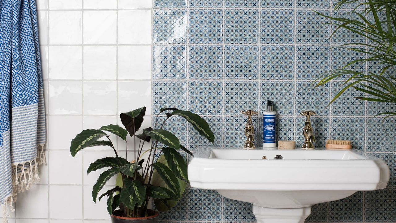 Traditional bathroom sink with blue patterned wall tiles and plain white wall tiles 