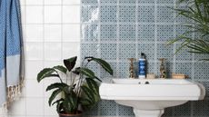 Traditional bathroom sink with blue patterned wall tiles and plain white wall tiles 