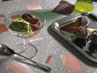 mint and chocolate gelato in glass cup on black and white marble countertop