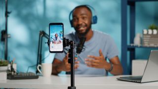 Man using mobile phone and videography equipment to record for podcast channel to create content