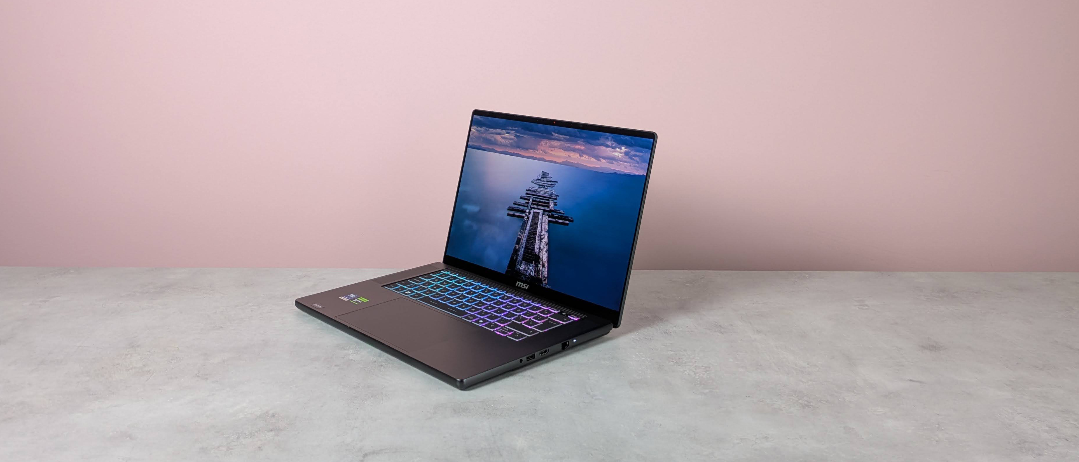 Three-quarter view of MSI Stealth 16 AI+ open on a white desk with pink wall in background