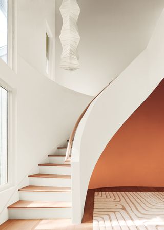 A staircase with white walls and orange painted walls in the entryway