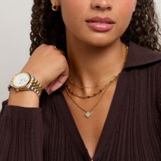 Model wearing a gold necklace stack and a gold and silver watch sold at Abbott Lyon