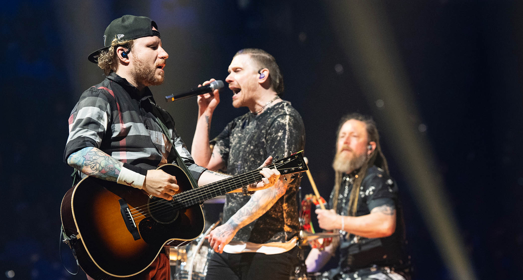 Shinedown's Zach Myers, Brent Smith and Barry Kerch perform live in New Orleans, 2025. Myers plays a tobacco sunburst acoustic and wears a ballcap.