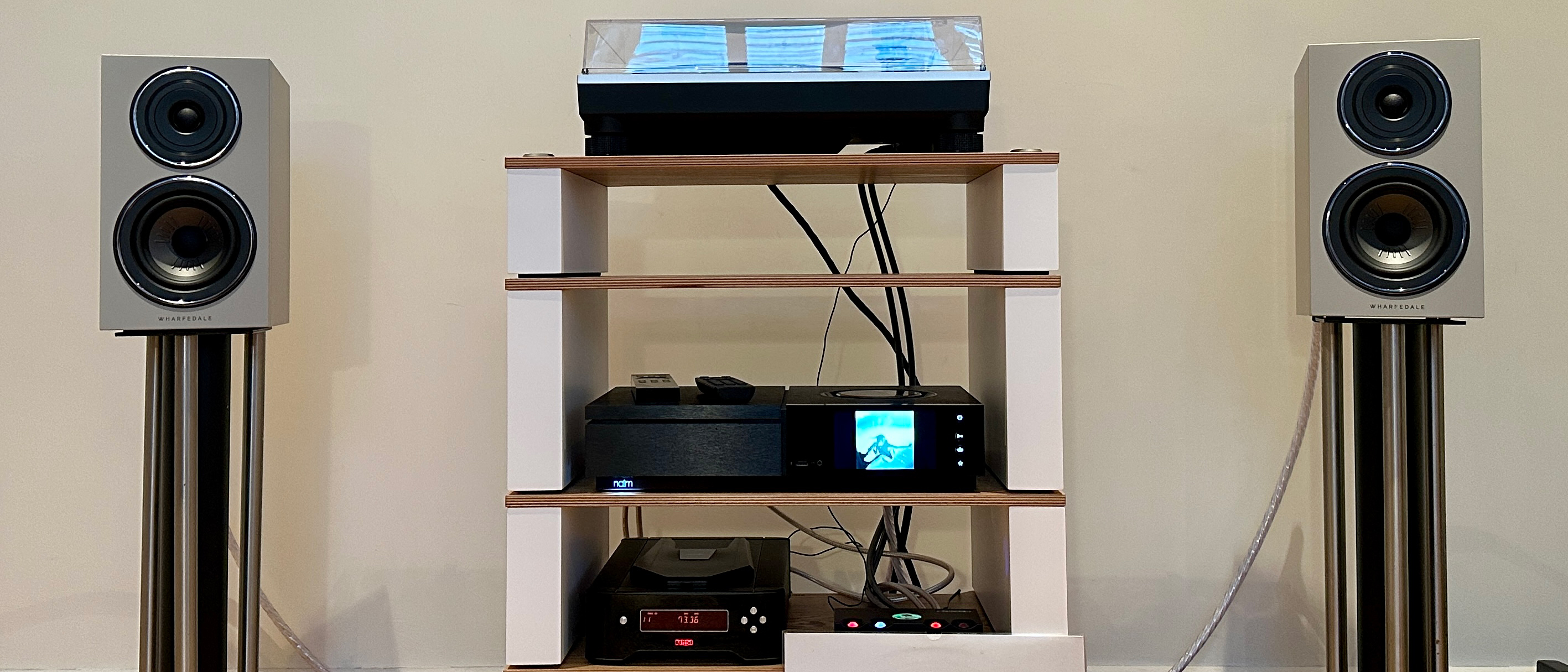 The Wharfedale Diamond 12.1i speakers on stands, on either side of a hi-fi setup with a Naim amp, plus a turntable and CD player