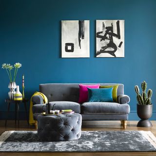 Teal painted living room wall with smart grey sofa and abstract artwork