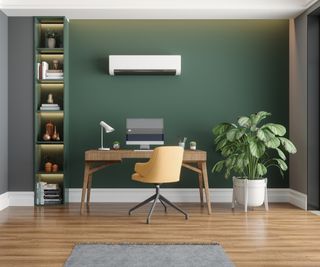 Tidy home office interior with yellow chair and wooden desk facing a dark green wall, with mounted white air ventilation system