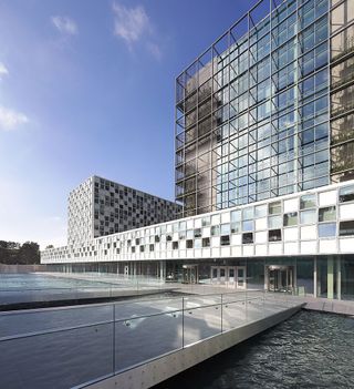 Schmidt Hammer Lassen’s design for the International Criminal Court. A bridge over water leading to one of the block shaped buildings.