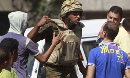 A soldier threatens Egyptians who try to get close to the Israeli embassy in Cairo: Demonstrators tore down a concrete wall and stormed the government building over the weekend.