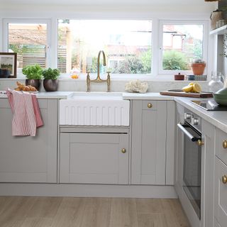 Grey shaker kitchen with white belfast sink and gold knob handles.