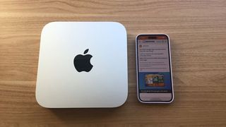 Mac mini (M2 Pro, 2023) with iPhone 14 beside it for scale