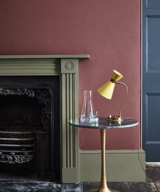 muted red wall with green fireplace and side table with yellow lamp