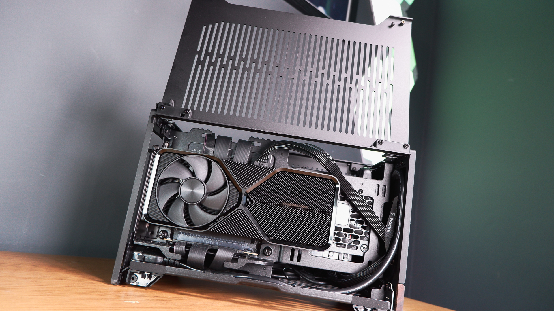 A compact gaming PC on a desk with various parts on show.