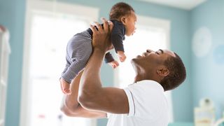 Why is sleep important: A man lifts his newborn son in the air