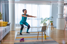 Beautiful African-American Woman Exercising Pilates, Yoga, Fitness at Home Looking at the Laptop