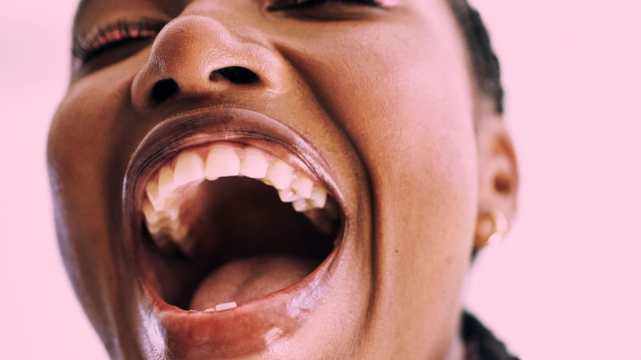 A woman wearing a plumping lip gloss while laughing