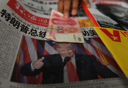 A 100 yuan note and a newspaper with Trump on it