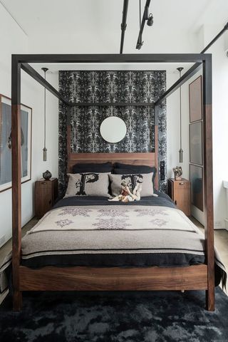 small bedroom with wooden four poster bed and black and grey wallpaper