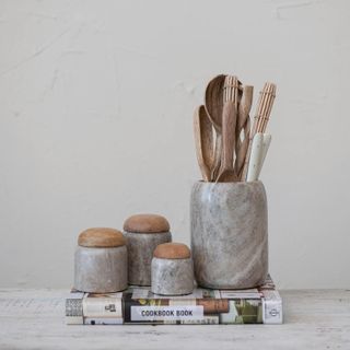 a collection of marble canisters, one filled with wooden spoons