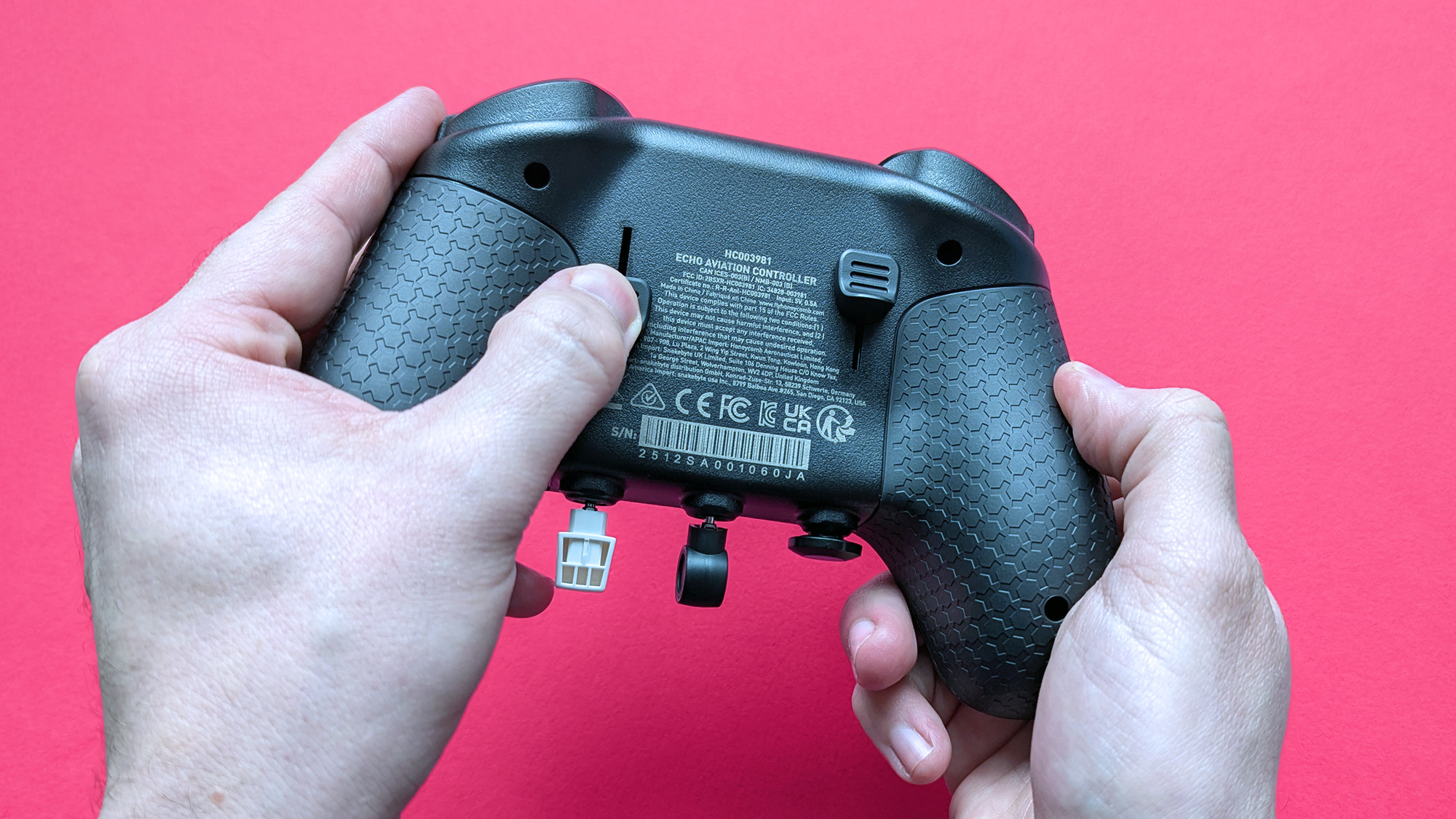 Honeycomb Aeronautical Echo Aviation Controller with a magenta cardstock background highlighting rudder controls on the rear