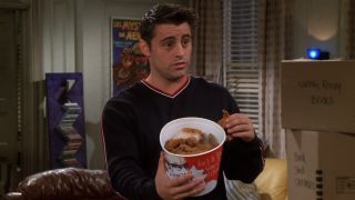 Joey Tribbiani (Matt LeBlanc) holds out a bucket of chicken on a Season 5 episode of Friends.