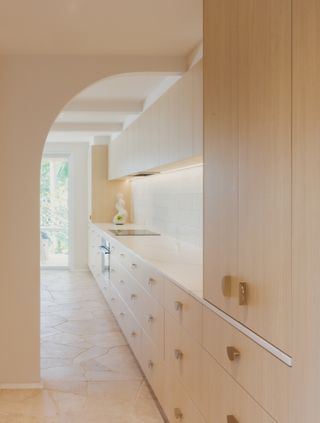 A kitchen with a light-toned countertop, and light wood cabients