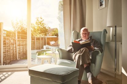 A man reads a book in a sunny room.