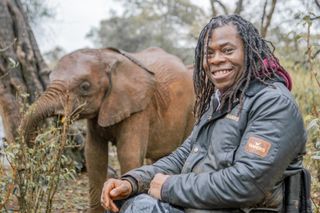 Ade Adepitan with a baby elephant in Kenya.