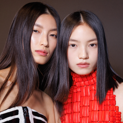 women with shiny hair backstage at Paris Fashion Week.
