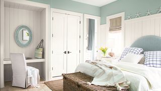 small bedroom with green painted walls and white wardrobes