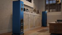 A pair of blue Magico A3 2027 floorstanding speakers flanking a cabinet in a living space.
