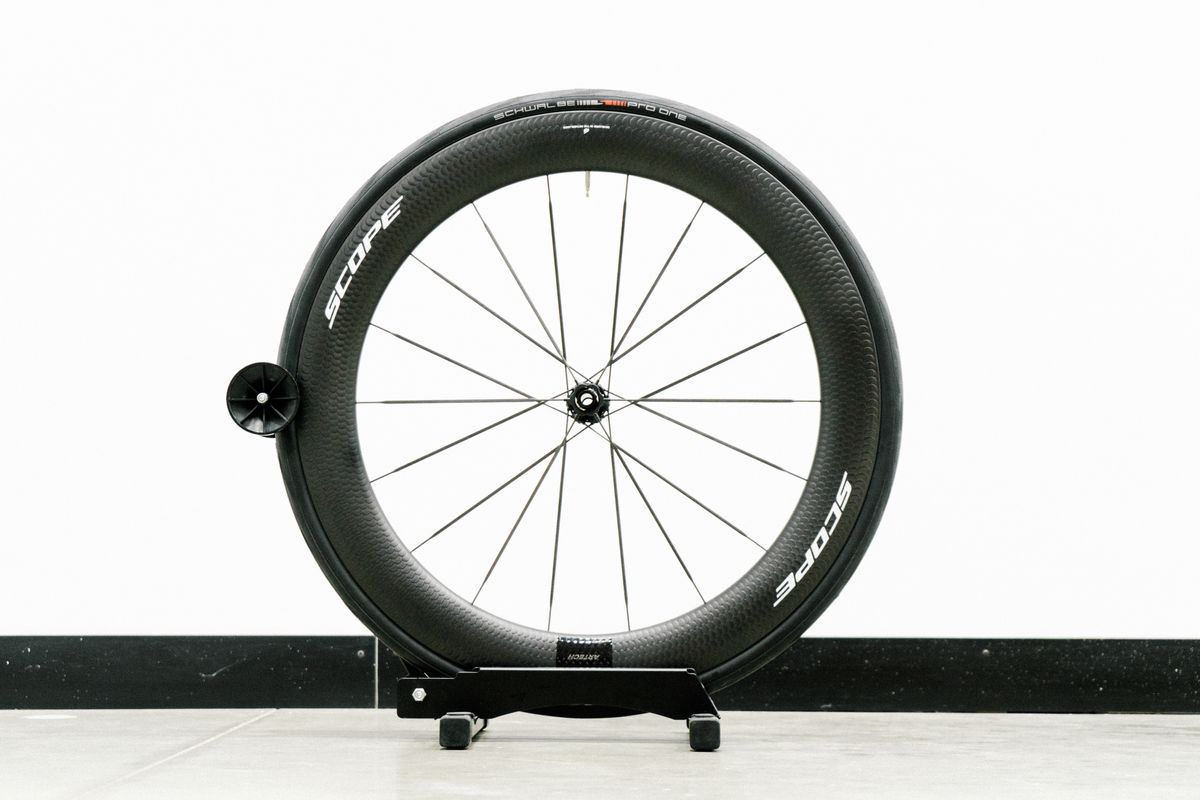 An aero road wheel stands against a white wall
