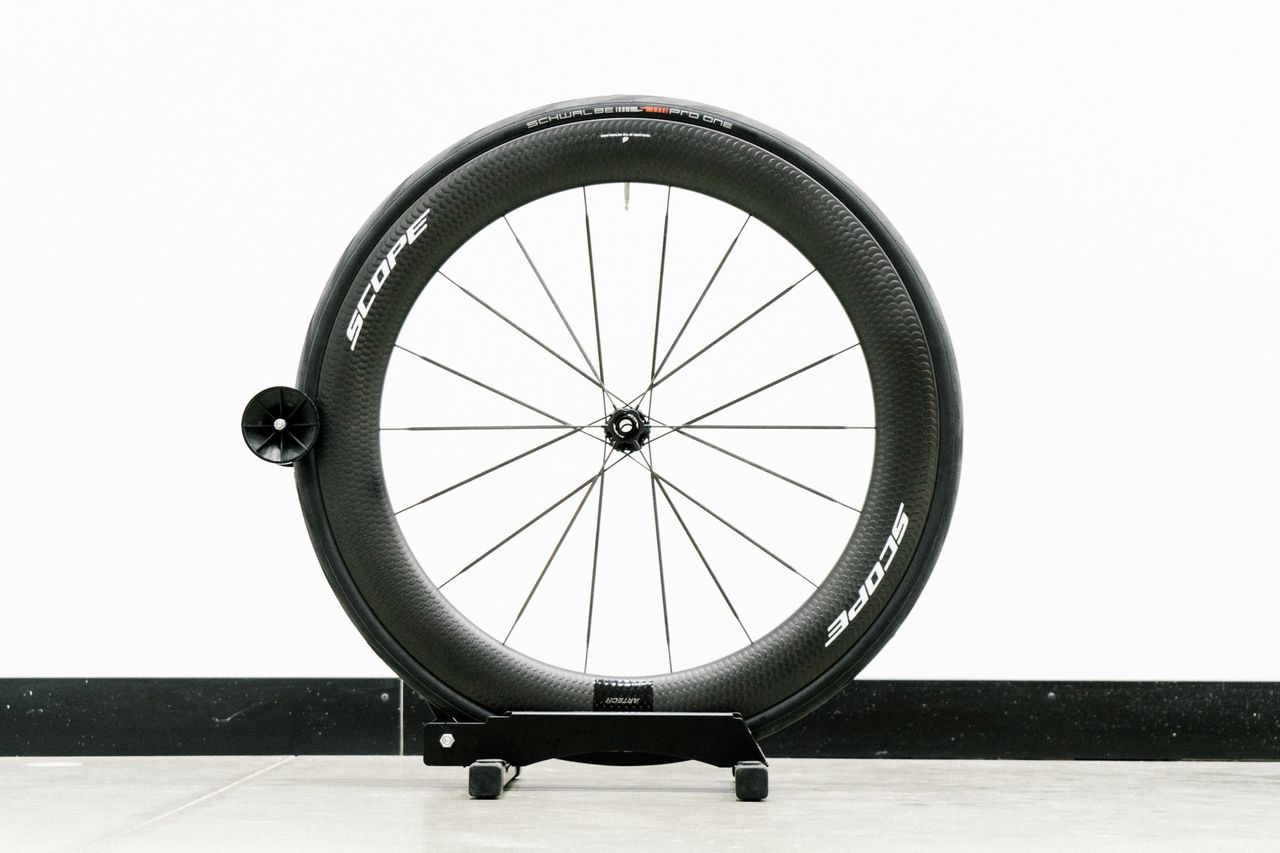 An aero road wheel stands against a white wall