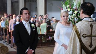Olly Rix in a morning dress as Matthew and Helen George as Trixie in a wedding dress stand in front of a vicar in the church in Call the Midwife.