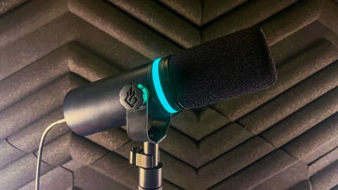 BEACN Mic pictured from the side in front of a soundproof wall panel - the RGB light is blue.