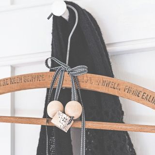 Wooden hanger with balls of cedar wood hanging from it by ribbon