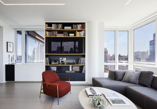 A modern apartment with a gray sofa and red accent chair