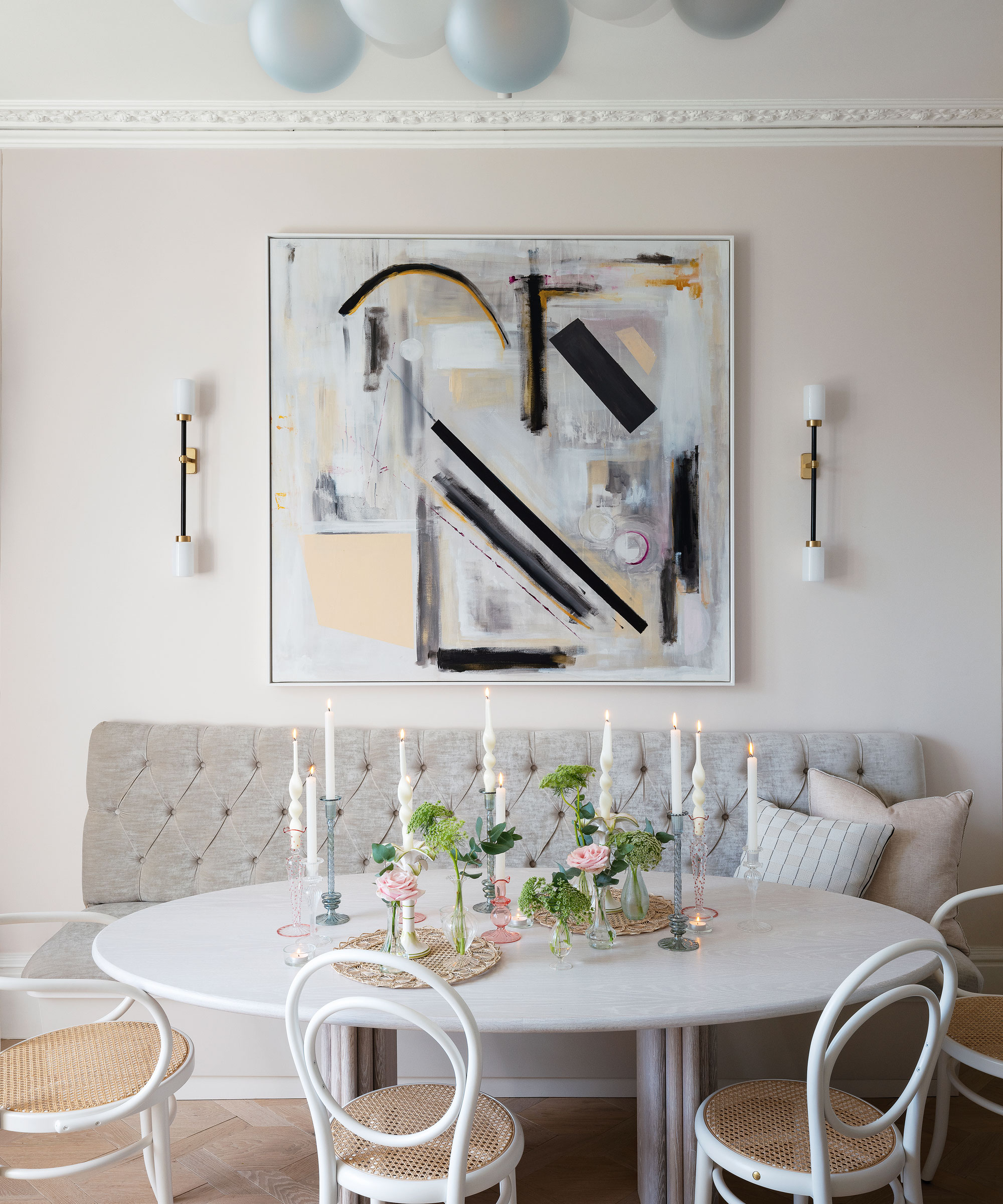 white kitchen dining area with white chairs, white circular table and light gray banquette