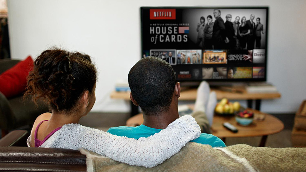 Kaksi henkilö katsoo Netflixiä sohvalla