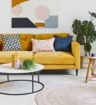 white living room with yellow sofa and canvas picture