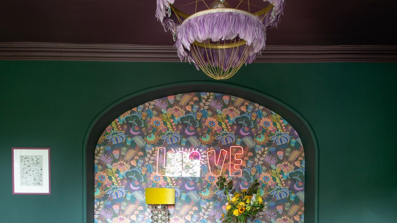 A living room with teal walls and a contrasting purple ceiling with a statement feather pendant light