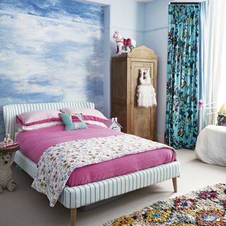 childrens bedroom with cloud wallpaper on wall and cushions on bed